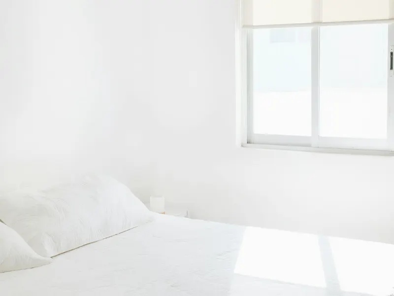 Sunlight falling across a neatly made bed with white linens